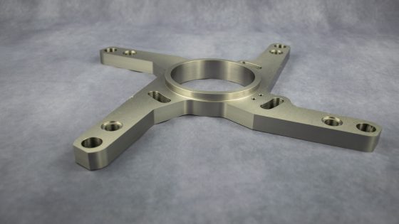 CNC-gefertigtes Bauteil mit kreisförmiger Mitte und vier Armen.